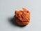 A ball of crumpled orange paper on a light background