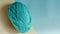 A ball of green yarn on a colored beige-turquoise background close-up,