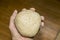Ball of homemade pizza dough gripped with one hand