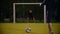 The ball lies on the grass in the foreground, the goalkeeper is at the gate, the other player kicks the ball, but does