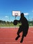 The ball in the player`s hands flies into the basketball ring on a sunny and clear day. Contour image of a basketball player. Mult