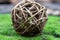 A ball of rattan, intertwined branches lies on the green grass. Close-up of the subject