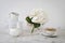 Ball-shaped white hydrangea in a round glass vase, set of light dishes, milk jug, porcelain and enameled cups, a jug for a