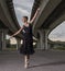 Ballerina in black outfit posing on toes,bridge background.