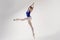 ballerina in a blue bodysuit and ballet shoes poses in a photo studio in motion showing beautiful long legs