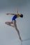 ballerina in a blue bodysuit and ballet shoes poses in a photo studio in motion showing beautiful long legs