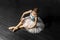 Ballerina dancing in a long peach dress on a black background.