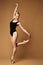Ballerina Dancing Modern Jazz Ballet. Dancer Exercise in Pointe Shoes. Slim Fit Body Woman in Action posing over Brown Studio