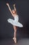 Ballerina dancing in white dress. Color photo. Graceful ballet dancer or classic ballerina dancing  on grey studio