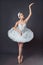 Ballerina dancing in white dress. Color photo. Graceful ballet dancer or classic ballerina dancing  on grey studio