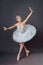 Ballerina dancing in white dress. Color photo. Graceful ballet dancer or classic ballerina dancing  on grey studio