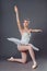 Ballerina dancing in white dress. Color photo. Graceful ballet dancer or classic ballerina dancing  on grey studio