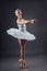 Ballerina dancing in white dress. Color photo. Graceful ballet dancer or classic ballerina dancing  on grey studio