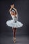 Ballerina dancing in white dress. Color photo. Graceful ballet dancer or classic ballerina dancing  on grey studio