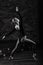 Ballerina in dark bodysuit, in dress in dark interior Studio. Wall of bricks, piano