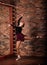 Ballerina in dark bodysuit, in dress in dark interior Studio. Wall of bricks, piano