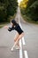 Ballerina female performing Classical ballet dance in forest on road at summer day