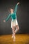 Ballerina in green leotard and skirt, dancing in the studio