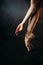 Ballerina hand and legs in pointes, black floor