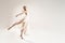 Ballerina in maxi dress dancing over light studio background. Ballet Dancer. Modern Dance. Graceful Woman. Hobby