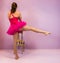 Ballerina performing a developpe, classical ballet move, view from the back, performed by a young transgender girl