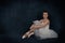 The ballerina in pointes and a white dress sits and rest