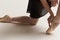 Ballerina puts pointe shoes on her feet White ribbon model dance light background.
