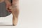 Ballerina puts pointe shoes on her feet White ribbon model dance light background.