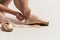 Ballerina puts pointe shoes on her feet White ribbon model dance light background.