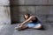 Ballerina sitting in profile on stone porch stretching over her pointe shoes