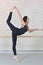 Ballerina stretches herself near barre at ballet studio, beautiful women in black bodysuit practicing ballet.