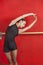 Ballerina Stretching With Arms Raised Against Red Wall