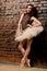 Ballerina in tutu near brick wall