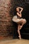 Ballerina in tutu near brick wall