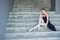 Ballerina in tutu posing sitting on the stairs A beautiful young woman in a black dress and pointe shoes is resting