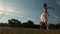 Ballerina in white dress dances on background of lawn and blue sky in the evening.