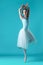 Ballerina in white dress posing on toes, studio background.