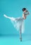 Ballerina in white dress posing on toes, studio background.