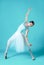 Ballerina in white dress posing on toes, studio background.