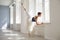 Ballerina. Young graceful ballet dancer is rehearsing a performance in a white studio with windows.