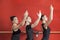 Ballerinas Practicing At Ballet Barre Against Red Wall