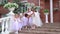 Ballerinas together with the teacher stand on a porch of school of the ballet and pose. Little ballerinas holding on to