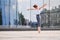 Ballet boy teenager dancing in a jump against background of city and sky reflections in a glass wall