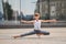 Ballet boy teenager trains standing on his hands against the background of the reflection of the city and sky in the glass wall