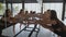 Ballet classes. Zoom in shot of ballerinas group training in dance studio, leaning forward with legs on barre at mirror