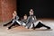 The ballet concept. Young ballerina girls relax sitting on the floor. Women at the rehearsal in a white tutu and a grey