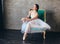 Ballet dancer ballerina in beautiful light blue dress tutu skirt posing sitting on vinage chair in loft studio