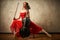 Ballet dancer in red dress and pointe playing on antique black cello