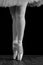 A ballet dancer standing on toes while dancing on black background