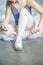 Ballet dancer tying slippers around her ankle